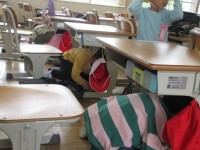 机の下に隠れる児童